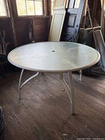 Side view of the round outdoor table showing powder-coated metal legs and frame