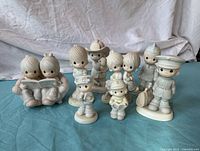 Photo of nine Precious Moments porcelain figurines arranged on a blue cloth background