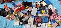 Overview photo showing large quantity of assorted miniature furniture pieces including sinks, chairs, tables, stoves, shelves in various colors and styles