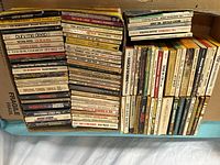 Stack of vintage paperback books showing various titles and worn conditions.