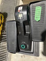 Full view of Cubii under desk elliptical showing textured foot pedals and compact black frame.