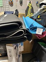 Side view of multiple rolled exercise and yoga mats piled horizontally on a table, showing different colors and thicknesses.