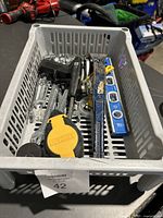 Photo of plastic basket with various hand tools including a yellow and black DEWALT tape measure, metal wrenches, blue spirit levels, a blue crowbar, wire cutters, and clamps.