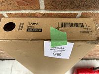 Close-up photo of the top side of the bookshelf box showing Ikea Laiva model, dimensions 62x165 cm, weight 13 kg, black-brown color code.