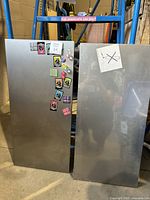 Front view of two metal magnetic boards, one with colorful magnets attached and some small notes, the other plain with a paper note.