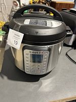 Diagonal front view of Instant Pot Duo Plus electric pressure cooker showing digital control panel and dent on lid.