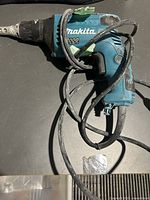 Makita FS4000 corded drill with blue and black housing, visible dust and wear, power cord wrapped around drill body.