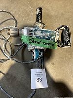 Makita drill with green tape labeled 'Good Tested' wrapped around the body, showing the full drill with power cord and handle.