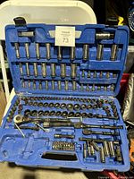 Open blue plastic case with multiple rows of sockets, ratchets, and accessories organized in molded slots.