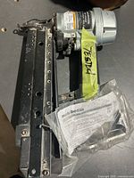 Overall angled view of Metabo HPT finish nailer showing black and silver metal body and air pneumatic motor with yellow tape tag