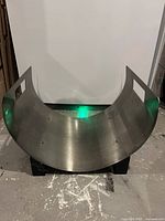 Front view of curved metal fire log holder with side handles.