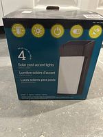 Front of box showing the set of 4 solar post accent lights in bronze finish, highlighting the product type and set quantity