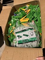 Box filled with green, yellow, blue, and clear tile wedges and spacers.