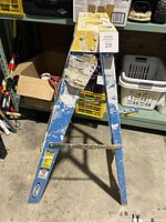 Full view of the Werner step ladder from the top, showing the yellow tool tray, four steps, paint splatters, and signs of heavy use.