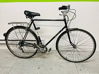 Side view of black Raleigh Sprite bicycle showing frame, wheels, rear rack, and handlebars