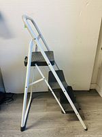 Side view of the white metal 3-step ladder showing steps, frame and safety handle.
