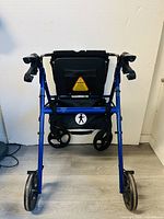 Full rear view of the blue foldable rolling walker, showing wheels, seat, and storage bag.