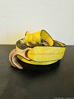 Yellow high strength tow rope with metal S-hook in focus, showing woven texture and sturdy construction.