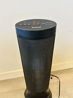 Full front view of a black Honeywell tower heater with mesh grille and control panel on top.