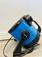 Side angle view of the blue Mastercraft space heater showing the black side control knob and mounting frame base.