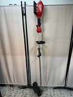 Full length photo of Milwaukee red and black cordless lawn trimmer with silver shaft and black trimming head