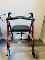 Front view of red BIOS rolling walker showing padded seat and handlebar with brake cables.