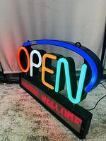 Multicolor "OPEN" LED neon sign with blue arch and red LED scrolling message panel located below, powered and lit on carpeted floor.