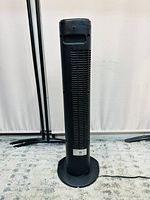 Front view of the black Sunbeam tower fan showing vertical air vents and circular base.
