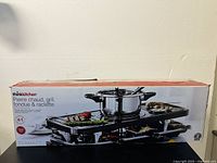 Photo of the product box showing branding and cooktop functions including pierre chaud (hot stone), grill, fondue & raclette features.