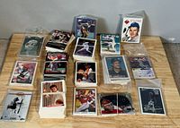 Photo of multiple stacks of baseball cards spread on a wooden table, showing different players and eras.