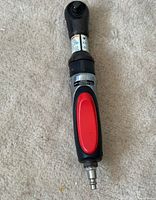 Front side view of COLEMAN pneumatic impact wrench with red grip and air hose connector on the base.