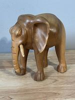 Front-left side view of the small carved wooden elephant on a surface.