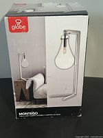 Photo of the boxed Globe Montego table lamp showing front with brand and product image.