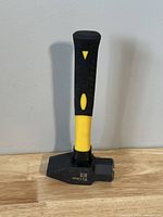 Front view of the Titan 3lb pein hammer showing the black and yellow rubber handle and black metal head with flat striking face and pein end.