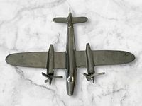 Top view of vintage aluminum airplane model showing twin propellers and streamlined body.