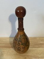 Front view of the vintage Italian decorative wine bottle showing detailed world map covering and wooden spherical stopper.