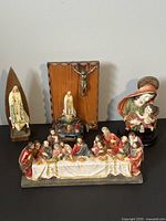 Lot of 4 vintage religious figurines displayed on a table including The Last Supper, Virgin Mary with Child, Our Lady of Fatima, and a crucifix on wood plaque