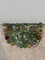 Overhead photo of 158 vintage glass marbles spread on carpet, showing variety of sizes and colorful swirl patterns.