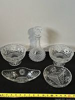 Photo of all five crystal glassware pieces showing the decanter with stopper, two pedestal bowls, an oval dish, and a round dish with intricate cut-glass patterns.