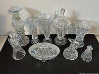 Full set of nine vintage crystal glassware pieces arranged on black surface showing cut designs and shapes