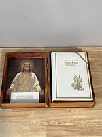 Open cedar wood box showing a white covered Memorial Edition Holy Bible and framed Jesus image with sympathy card inside lid.