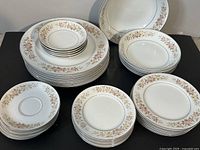 Full lot of 31 pieces of vintage Nitto La Scala 4914 dinnerware showing stacked plates and bowls with floral rim pattern.