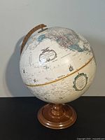Vintage Replogle world globe with wooden base and brown meridian arm shown from an angled left side, displaying geographic details primarily of the Pacific Ocean and surrounding continents.