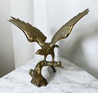 Front view showing eagle wings fully spread perched on stylized branch base