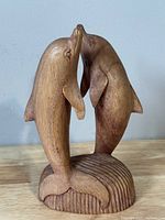 Front angled view showing the two dolphins touching noses and the ribbed textured base.