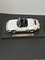 White Maisto 1989 Porsche 911 Speedster diecast model on black display base with gold plaque.