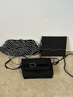 Three vintage women's bags shown side by side on carpet: black and white striped fabric bag, black quilted fabric bag with rhinestones, black evening clutch with buckle.