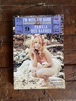 Front cover photo of the book showing the title, author, and a photo of a young woman sitting nude outdoors on a rock by a creek with flowers.