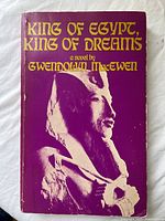 Front cover of the paperback book showing title, author, and Egyptian statue image on purple background.