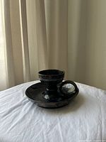 Angled view of the black flatstone chamber candlestick holder showing the candle cup, handle, and wide base.